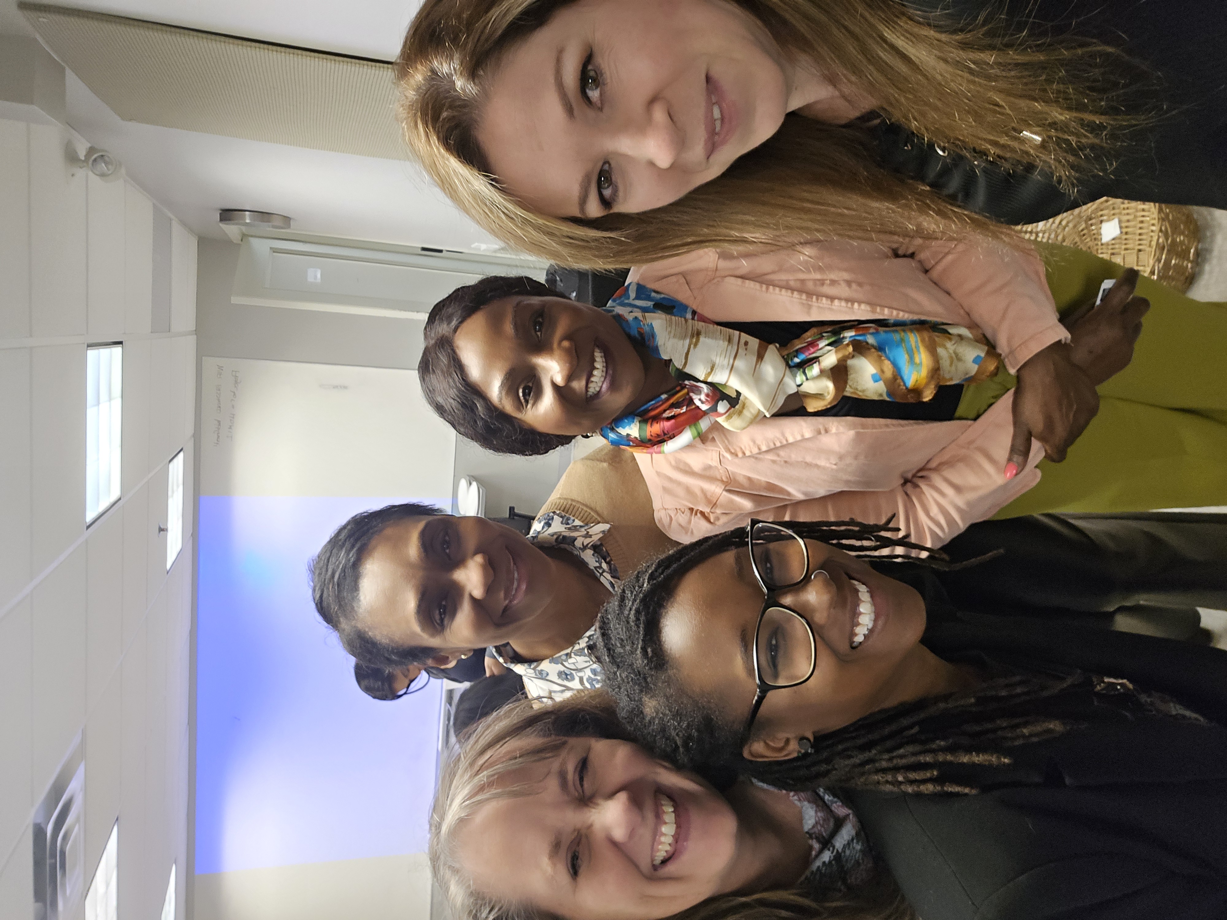 Image of a diverse group of women smiling for the camera in a meeting room